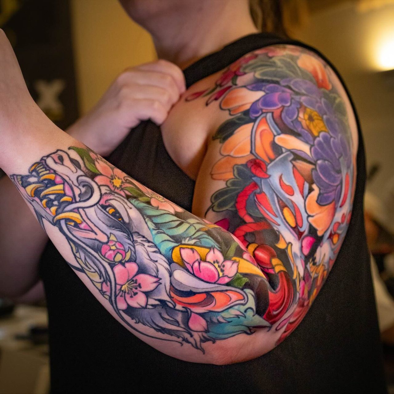 Nahaufnahme eines farbigen Oberarm-Tattoos mit Tier- und Blumenmotiven von Luiz Lacorte, umgesetzt im Electric Eel Tattoo Studio in Köln-Ehrenfeld.